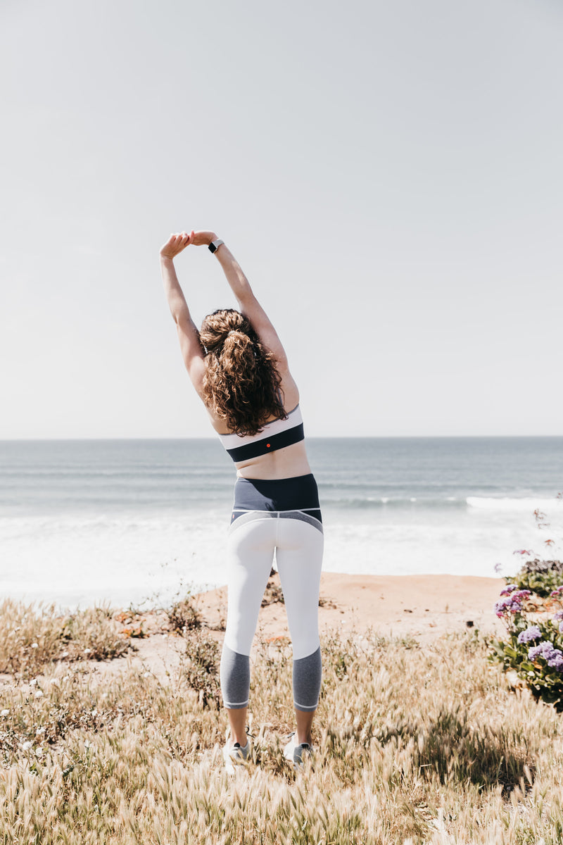 Woman on the beach doing a yoga pose in the VIMMIA Perception Crop